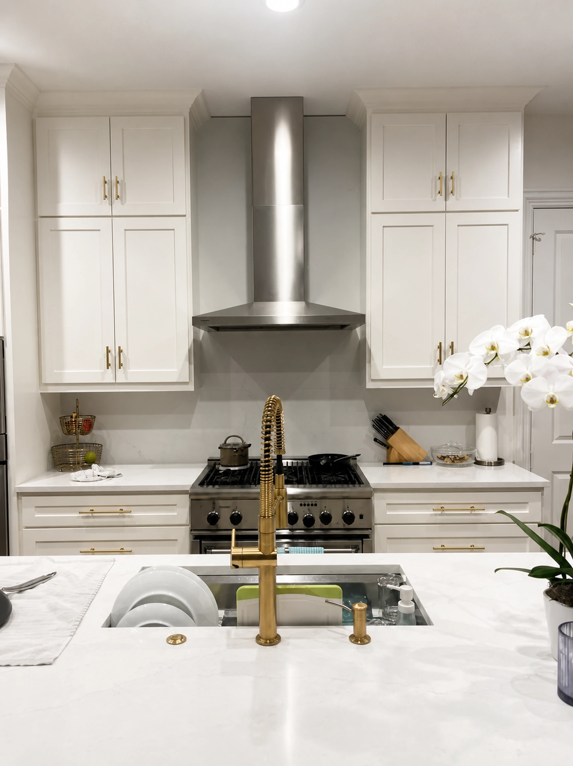 Modern white kitchen with brass fixtures and range hood
